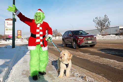 15122025
The Grinch, aka Jennifer Botham, walks her dog Romio along 18th Street in Brandon, waving to passing vehicles and spreading Christmas cheer on Monday.
(Tim Smith/The Brandon Sun)