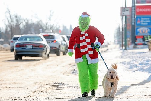 15122025
The Grinch, aka Jennifer Botham, walks her dog Romio along 18th Street in Brandon, waving to passing vehicles and spreading Christmas cheer on Monday. 
(Tim Smith/The Brandon Sun)
