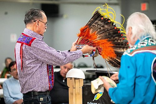 MIKAELA MACKENZIE / FREE PRESS

Councillor (and grandson of chief Angus Merrick) Randy Merrick sets the headdress on a stand during a repatriation ceremony at Long Plain First Nation urban reserve in Portage la Prairie on Tuesday, Dec. 16, 2025. 

For CP story.
Free Press 2025