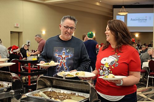 Andrea and Marc Plante prepare to serve a hot meal to people sitting at tables at the Victoria Inn for the Westman and Area Traditional Christmas Dinner on Thursday. (Tessa Adamski/The Brandon Sun)