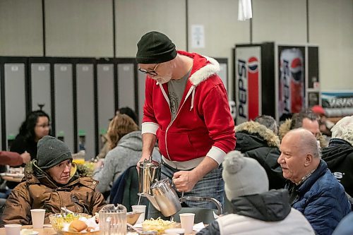 BROOK JONES/FREE PRESS
As many as 600 meals were expected to be given out during a Christmas dinner at Mission Baptist Church in Winnipeg, Man., Thursday, Dec. 25, 2025. Pictured: Rex Ferguson-Baird serves tea while volunteering at the Christmas dinner with his wife Bonnie and their daughter Bridget.
