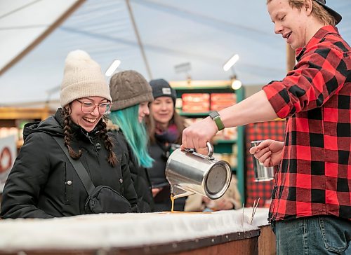 BROOK JONES/FREE PRESS
Gabrielle Walkty, 18, (left) is all smiles while volunteer Theodore Funk pours hot maple syrup on snow to make frozen maple taffy in the Sugar Shack on the final day of the 57th edition of Festival du Voyageur in Saint Boniface, Man., Sunday, Feb. 22, 2026.