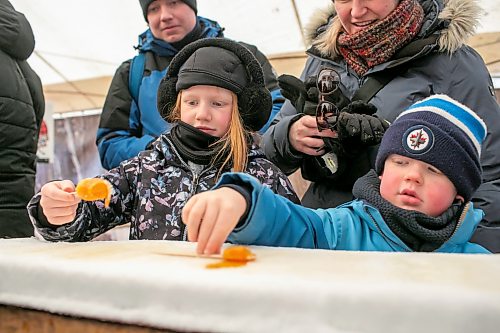 BROOK JONES/FREE PRESS
Blake Leslie, 9, and her brother Rhys Leslie, 5, are pictured rolling frozen maple taffy on a stick in the Sugar Shack on the final day of the 57th edition of Festival du Voyageur in Saint Boniface, Man., Sunday, Feb. 22, 2026.