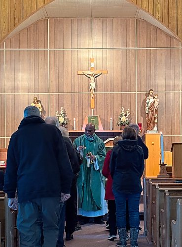 MELISSA MARTIN / FREE PRESS

Rev. Fr. Philip Malayil gives communion to about 25 worshippers at St. James' Church in Baldur. 
