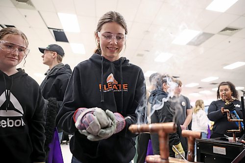 Mia Fleming with Boissevain School watches as classmate Kaitlynn Janssens practises soldering pipes at the Piping Industrial Technical College booth. (Tim Smith/The Brandon Sun)