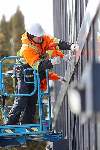 A worker uses a mallet to attach metal trim to a new window at city hall. (Matt Goerzen/The Brandon Sun)