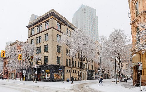 MIKE DEAL / FREE PRESS
Snow falls as pedestrians make their way through the Exchange District Wednesday morning.
260408 - Wednesday, April 08, 2026.