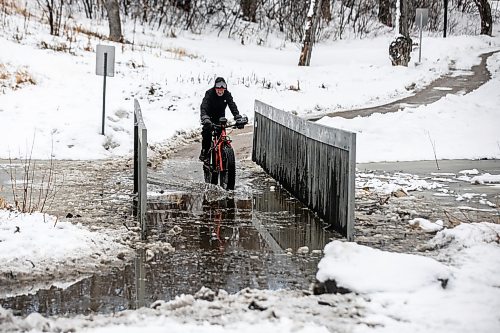 MIKAELA MACKENZIE / FREE PRESS
Steven Sangster bikes across the flooded pedestrian bridge at Omandճ Park on Wednesday, April 8, 2026.
Standup.
Free Press 2026