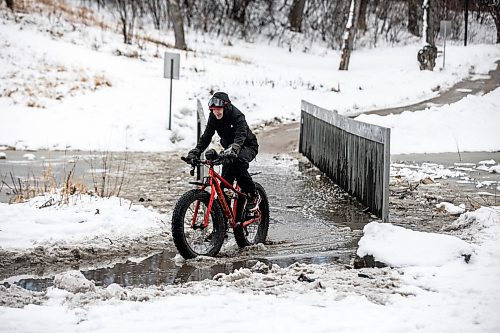 MIKAELA MACKENZIE / FREE PRESS
Steven Sangster bikes across the flooded pedestrian bridge at Omandճ Park on Wednesday, April 8, 2026.
Standup.
Free Press 2026