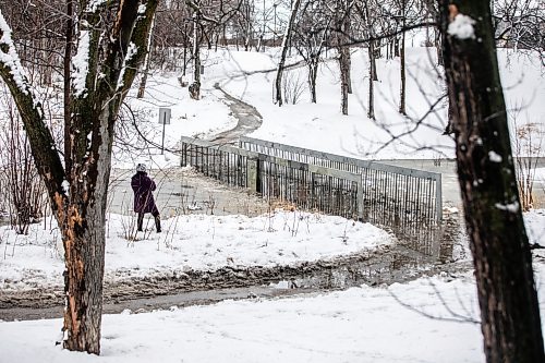 MIKAELA MACKENZIE / FREE PRESS
	
Sally Ito checks out the flooded pedestrian bridge at Omandճ Park on Wednesday, April 8, 2026.

Standup.
Free Press 2026