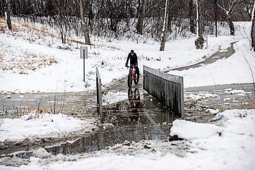 MIKAELA MACKENZIE / FREE PRESS
Steven Sangster bikes across the flooded pedestrian bridge at Omandճ Park on Wednesday, April 8, 2026.
Standup.
Free Press 2026