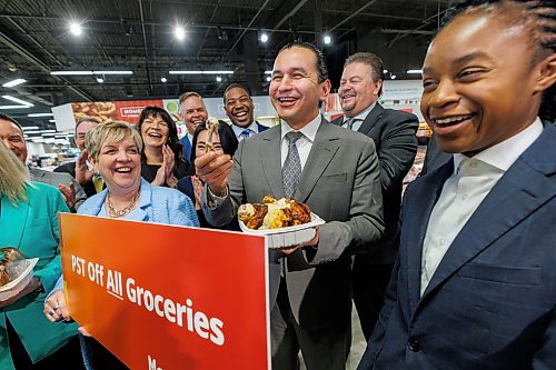 MIKE DEAL / FREE PRESS
Premier Wab Kinew takes a bite out of a rotisserie chicken surrounded by most of his cabinet at the Red River Co-op, 1120 Grant Ave, Wednesday afternoon, to reiterate one of the parts of the newly tabled budget, removing the PST from groceries.
260325 - Wednesday, March 25, 2026.