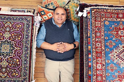 Yousaf Chaman, director for the Bunyaad program, lies alongside of some of the 268 hand-woven Pakistani rugs and pillows available for sale at Ten Thousand Villages on Rosser Avenue in Brandon on Thursday. Bunyaad is a fair-trade program that works with artisan families in Pakistan. See story on page A2. (Tim Smith/The Brandon Sun)