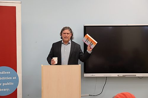 Mayor Jeff Fawcett holds a copy of "Empire of AI: Dreams and Nightmares in Sam Altman’s OpenAI" by Karen Hao during his book club discussion at the Brandon Public Library on Thursday evening. (Abiola Odutola/The Brandon Sun)