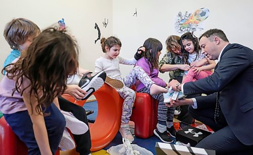 Finance Minister Adrien Sala helps a Grade 1 student, Emilie, put on her new shoes while handing out new shoes as part of a pre-budget event at Linwood Childcare Centre in March. (Ruth Bonneville/Winnipeg Free Press files)