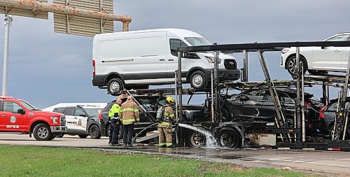 A Brandon firefighter sprays water into the section of the truck transporting seven vehicles that caught fire on the eastbound lanes of the Trans-Canada Highway near Brandon on Friday afternoon. Photos: Abiola Odutola/The Brandon Sun