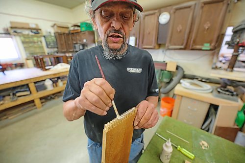 Mike Stuart, a refinisher with nearly 30-years experience working at Persnickety, brushes glue onto the joints of a filing cabinet that a customer is having repaired. The cabinet is branded for an old company in Aberdeen, S.D. called News Printing Co., and features wooden dividers for organizing files. Stuart completely disassembled the piece, which was warped and non-functional, and repaired it by hand with various methods such as filling in imperfections, sanding it into shape, and buffing down brass accents so that they shine again. (Connor McDowell/The Brandon Sun)