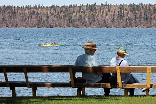 Kayakers paddle on Clear Lake in Riding Mountain National Park as other visitors sit on a bench on a sunny Monday afternoon. Environment Canada is forecasting a high of 27 C for Brandon today, with the temperature rising to a scorching 35 C later in the week. (Tim Smith/The Brandon Sun)