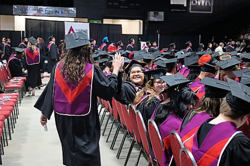 Culinary Arts graduate Brianna Bone gives a friend a high-five during the college's graduation ceremony on Friday morning in the main arena of Assiniboine Credit Union Place. (Abiola Odutola/The Brandon Sun)