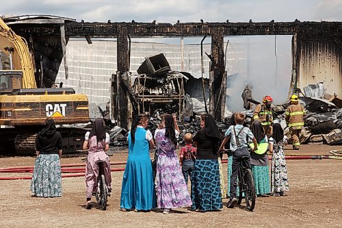 Colony members watch as firefighters from the Oakland-Wawanesa Fire Department, the Souris-Glenwood Fire Department and Green Acres Colony worked to put out a fire that destroyed the colony’s garage next to its mechanic shop and several vehicles on Thursday. (Tim Smith/The Brandon Sun)
