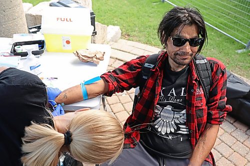 24062026
Robert Stevens sits as Kelly Aldcroft, a public health nurse with Prairie Mountain Health, takes blood for sexually transmitted and blood-borne infections testing during a national testing day event hosted by the Manitoba Harm Reduction Network at Princess Park on Wednesday. The event included resource booths, naloxone and harm reduction supplies, crafts, games, food and immunization availability.
(Tim Smith/The Brandon Sun)