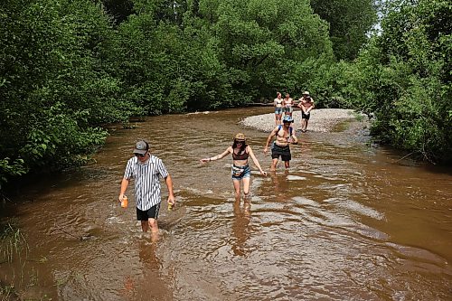 26062026
Festival-goers wade through the creek that runs past the campground area at Dauphin’s Countryfest 2026 on Friday afternoon.
(Tim Smith/The Brandon Sun)