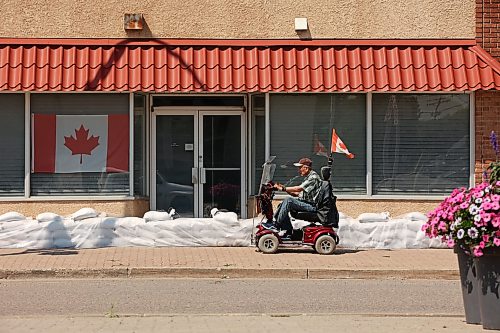 A person passes by a building in downtown Minnedosa protected by sandbags on Friday in preparation for flooding from the Little Saskatchewan River. (Tim Smith/The Brandon Sun)