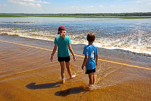 13072026
Siblings Emily and Brooks Zamrykut wade in the flood waters of the Assiniboine River pouring over Grand Valley Road near the Trans Canada Highway on a scorching hot Monday afternoon.
(Tim Smith/The Brandon Sun)