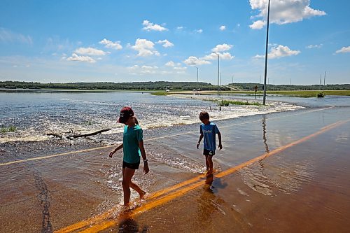 13072026
Siblings Emily and Brooks Zamrykut wade in the flood waters of the Assiniboine River pouring over Grand Valley Road near the Trans Canada Highway on a scorching hot Monday afternoon.
(Tim Smith/The Brandon Sun)