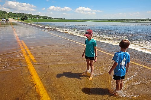 13072026
Siblings Emily and Brooks Zamrykut wade in the flood waters of the Assiniboine River pouring over Grand Valley Road near the Trans Canada Highway on a scorching hot Monday afternoon.
(Tim Smith/The Brandon Sun)