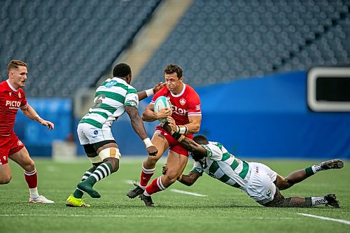 BROOK JONES/FREE PRESS
Team Canada player Kyle Tremblay (No. 14) runs with the ball while Team Zimbabwe player Tinotenda Mavesere (No. 6) and Zimbabwe teammate Brandon Mudzekenyedzi (No. 13) try to tackle him during first half action at Princess Auto Stadium on Saturday.