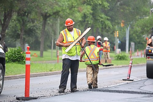 Work crews move and smooth out asphalt with rakes and shovels during road construction on Richmond Avenue on Tuesday afternoon. (Matt Goerzen/The Brandon Sun)