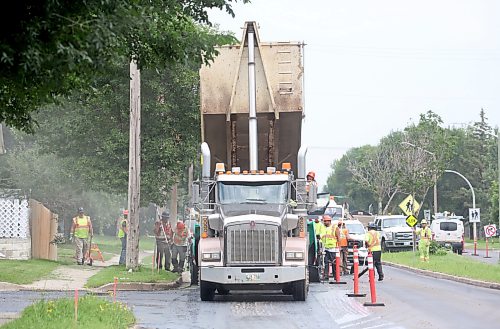 A dump truck feeds hot asphalt into a pacing machine that spreads it evenly along the right lane of westbound Richmond Avenue on Tuesday afternoon. (Matt Goerzen/The Brandon Sun)