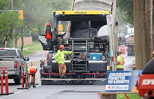 A dump truck feeds hot asphalt into a pacing machine that spreads it evenly along the right lane of westbound Richmond Avenue on Tuesday afternoon. (Matt Goerzen/The Brandon Sun)