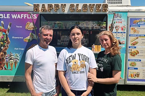 Veronika Plis (centre) joins her parents, Roman and Nataliia Zhuniak, owners of Happy Clover food truck, in front of their truck during the 2026 Souris Peacock Days & Fair recently. The Ukrainian family, which settled in Neepawa four years ago, turned an idea born from community observation into a new local business. (Abiola Odutola/The Brandon Sun)