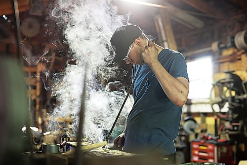 Gregory Reimer brands a piece of wood in the blacksmith shop. (Tim Smith/The Brandon Sun)