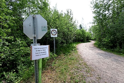 Ruth Bonneville / Free Press
Local RCMP update Nutimik search
Photo of sign at the beginning of the path that leads to Sturgeon Falls Trail, where the boys slipped into the rapids at Camp Nutimik.
Story: RCMP confirmed at presser at the boat launch at Nutimik Lake that the body of the missing 10-year-old boy has been recovered following days of an intensive search near the falls at Nutimik Lake. Search and rescue teams including the RCMP, charitable organizations, local businesses and the members of the public continue to search for his 13-year-old brother.
Two boys, aged 10 and 13, slipped into the fast-moving rapids near Sturgeon Falls Trail in Manitoba's Nutimik Lake last Saturday, July 18th while with family,
See story by Moe
July 23rd, 2026
