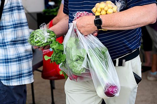 Mike Sudoma / Free Press
A shopper with two hands full of produce waits in line to pay Saturday morning
July 25, 2026