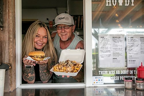 BROOK JONES/FREE PRESS
Star Giesbrecht and her husband Lee Giesbrecht opened the Starlette's Burger Saloon at 60122 Juno Rd., just north of Elma, Man., in May 2025 after Lee made the dining patio to like an old-fashioned, western saloon from recovered barn wood. Pictured: Star (left) holds a Big Wild West Burger while Lee holds a dish of Buckin Poutine on Saturday, July 25, 2026.
