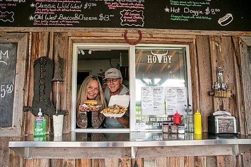 BROOK JONES/FREE PRESS
Star Giesbrecht and her husband Lee Giesbrecht opened the Starlette's Burger Saloon at 60122 Juno Rd., just north of Elma, Man., in May 2025 after Lee made the dining patio to like an old-fashioned, western saloon from recovered barn wood. Pictured: Star (left) holds a Big Wild West Burger while Lee holds a dish of Buckin Poutine on Saturday, July 25, 2026.
