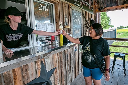 BROOK JONES/FREE PRESS
Star Giesbrecht and her husband Lee Giesbrecht opened the Starlette's Burger Saloon at 60122 Juno Rd., just north of Elma, Man., in May 2025 after Lee made the dining patio to look like an old-fashioned western saloon from recovered barn wood. Pictured: Employee Breeze Richardson (left) serves an ice cream cone to Preeth Lein, who is from Brokenhead Ojibway Nation, on Saturday, July 25, 2026. It was Lein's first time visiting the Starlette's Burger Saloon.
