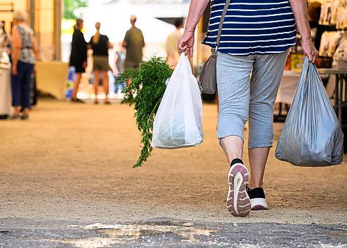 Mike Sudoma / Free Press
A shopper with two full grocery bags walks through the inside of the St Norbert Farmers Market Saturday morning
July 25, 2026