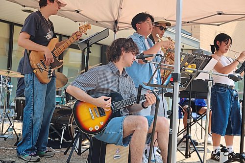 Awiitin, a band from Winnipeg, plays at the Brandon Summer Market on Wednesday afternoon. The band played renditions of “Love Never Felt So Good,” and “Superstition” during their show with a drum kit, a bass guitar, a saxophone, two trumpets and a guitar. (Connor McDowell/The Brandon Sun)