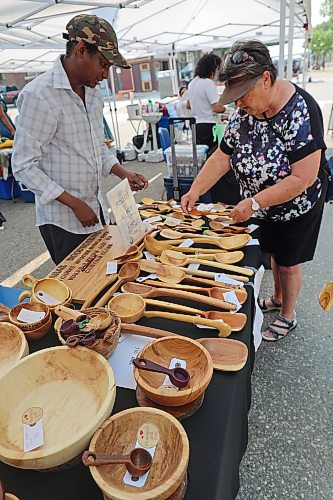Mubarak Ugas showcases some of his hand carved wooden spoons and bowls to guests at the Brandon Summer Market on Wednesday afternoon. (Connor McDowell/The Brandon Sun)