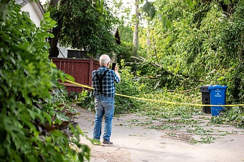 MIKAELA MACKENZIE / FREE PRESS
	
Neighbour Jake Falk checks out storm damage in the alley behind Stewart Street on Thursday, July 30, 2026.

For Chris story.
Free Press 2026