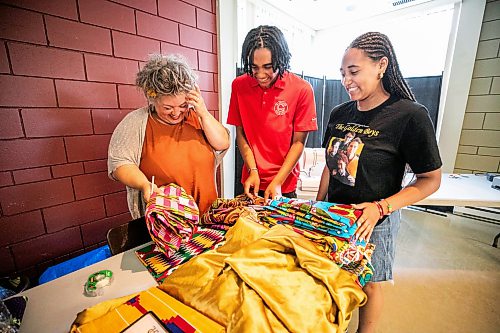 MIKAELA MACKENZIE / FREE PRESS
	
Volunteer Jaelynne Wormenor (left) and pavilion ambassadors Kataali Stoller and Tunteya Stoller look through fabric while working to replace cultural costumes (after the outfits were stolen from a parked vehicle) at the Notre Dame Recreational Centre on Friday, July 31, 2026.

For Chris story.
Free Press 2026