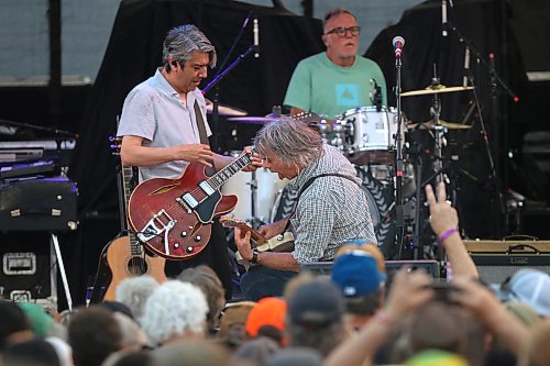 54-40 singer and guitarist Neil Osborne stick out his tongue as lead guitarist David Genn leans into a solo in front of drummer Matt Johnson during Rockin’ the Fields of Minnedosa on Sunday. (Perry Bergson/The Brandon Sun)