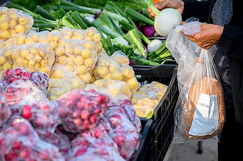 Mike Sudoma / Free Press
A shopper with a loaf of bread looks over an onion Saturday morning at the St Norbert Farmers Market
July 25, 2026