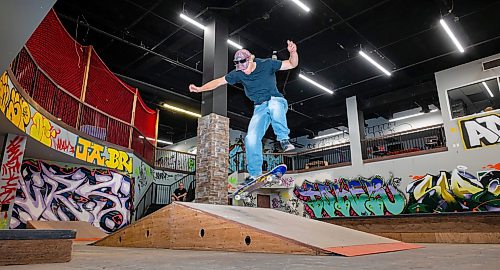 ROBERT LEE / FREE PRESS
Fane Smeall, Pitikwe manager and skater, rides a ramp at the Pitikwe Skatepark in downtown Winnipeg on Thursday, August 6, 2026.  Roger West, security, looks onwards from the staircase. The indoor park, formerly in Portage Place, relocated earlier this year to a former Snap Fitness beside the APTN building, continuing the city’s tradition of skateboarders creating their own year-round hubs.