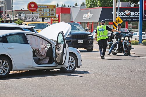A Brandon Police officer directs traffic in the northbound lane of 18th Street as emergency crews check the damage to one of two vehicles involved in a collision at the Park Avenue and 18th Street intersection on Friday during the noon hour. Airbags are clearly visible on the passenger side of the vehicle, though Brandon Police indicated later Friday afternoon that there were no known injuries as a result of the collision. (Matt Goerzen/The Brandon Sun)